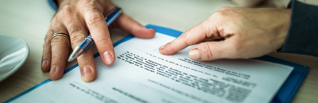 A close-up image of two people's hands pointing to the bottom of an official document.